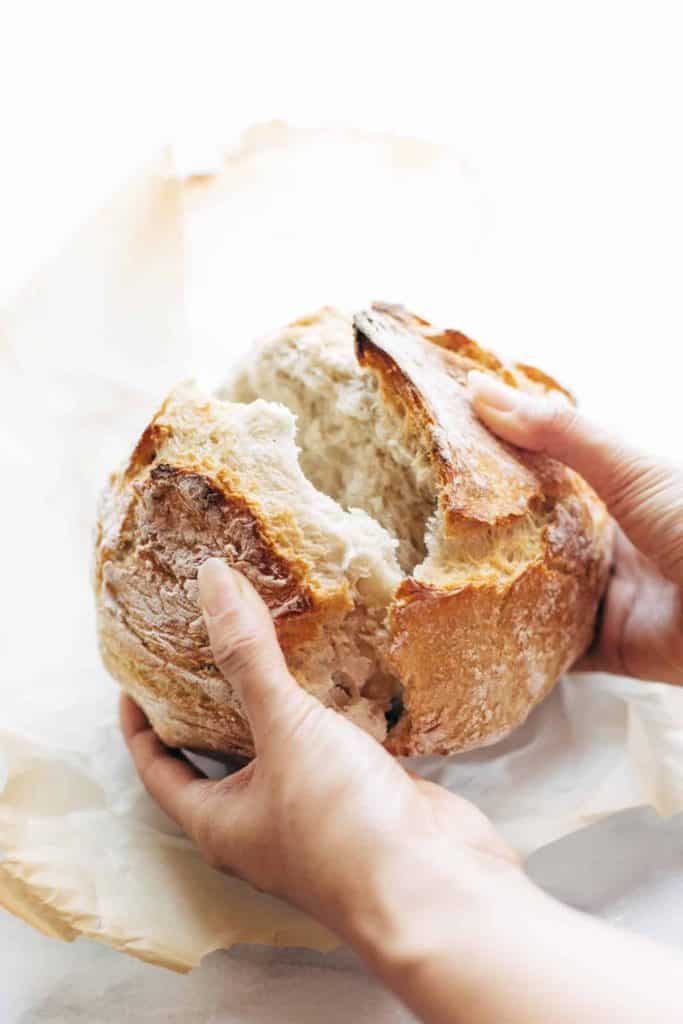 Round loaf of homemade bread being pulled open